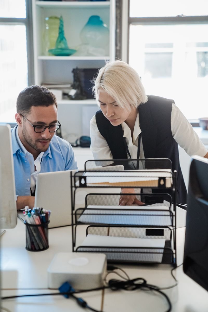 Colleagues reviewing a laptop screen in a bright office