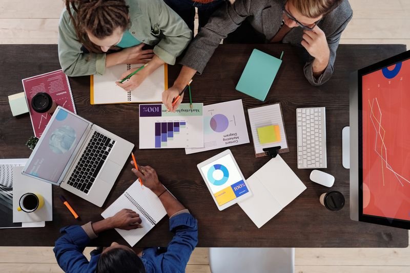 Overhead view of a team collaborating with a laptop and charts
