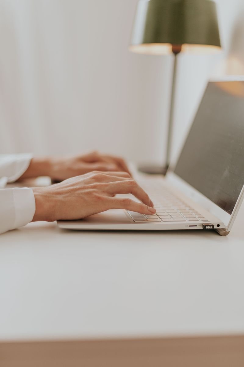 Hands typing on a laptop in a bright minimal office