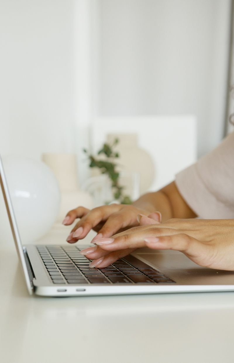 Hands typing on a MacBook in a bright minimal room
